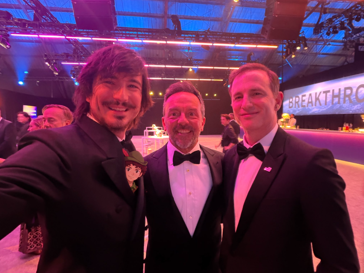Community photo edit: Little Guy's head peeks from Vlad Tenev's suit at an event with two other guests.